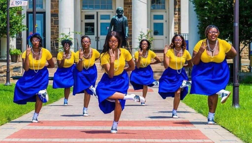Seven members of Sigma Gamma Rho dressed in 1950s style with poodle skirts, saddle shoes and cat eye glasses.