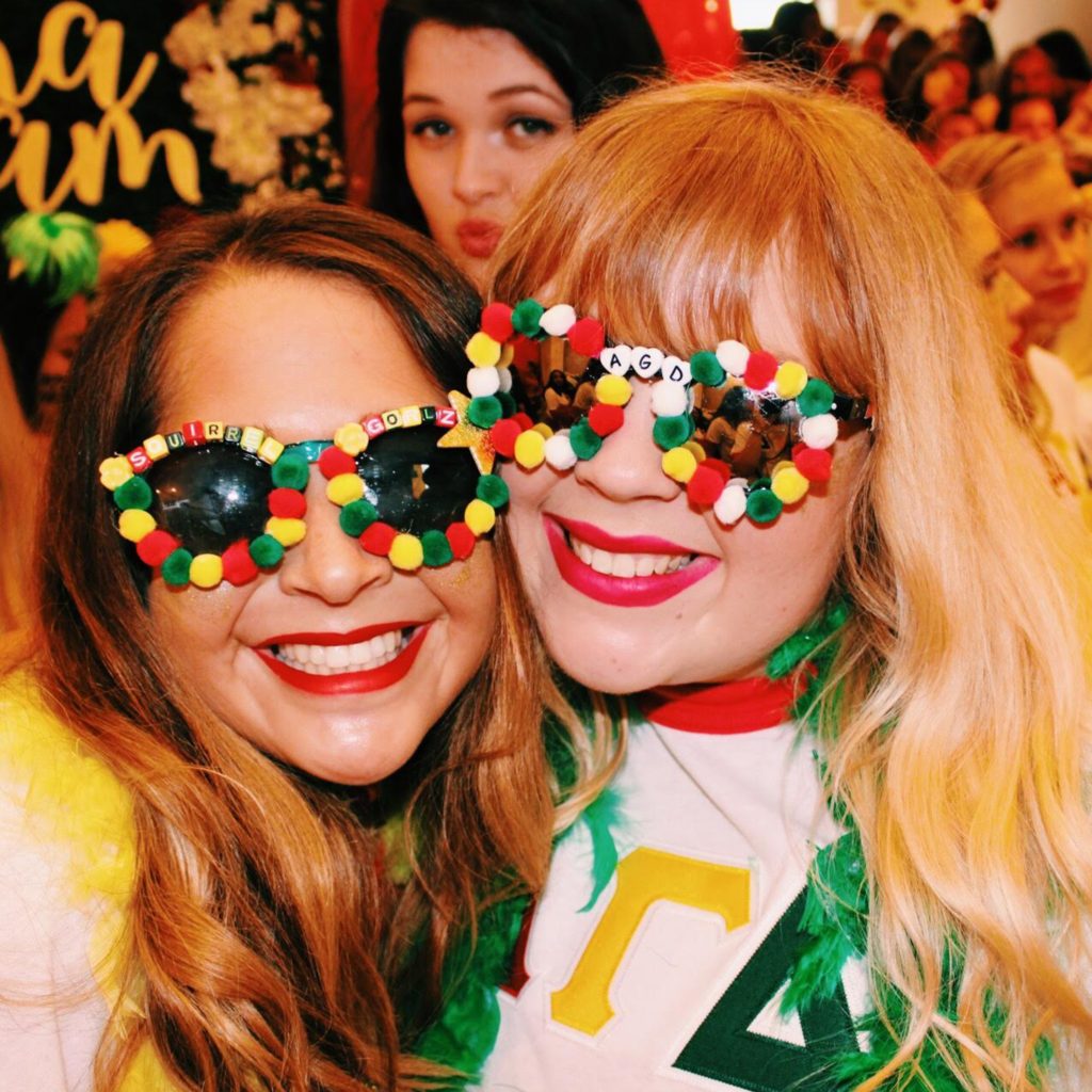 Two Alpha Gamma Delta members on Bid Day. They are wearing red, buff and green accessories.