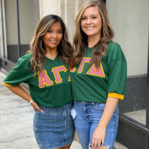 Two Alpha Gamma Delta Members wearing matching green shirts with AGD letters on it.